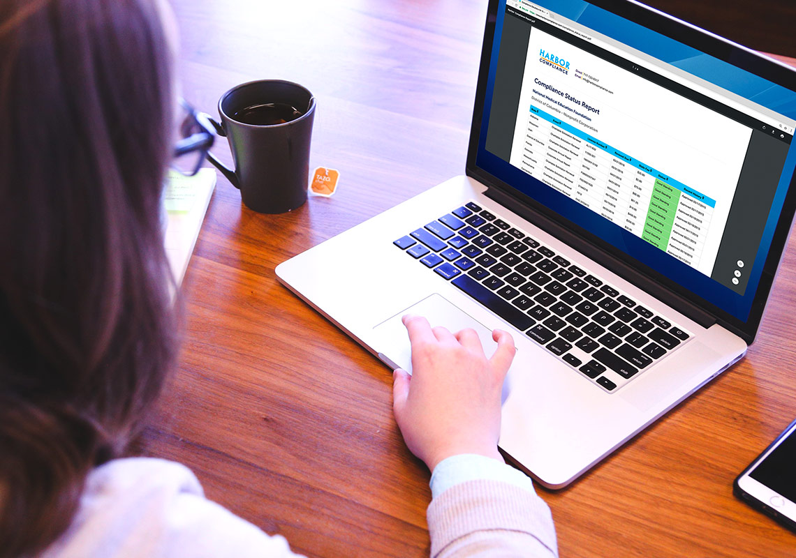 A woman on a laptop checking her Compliance Status Report